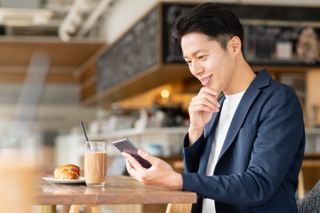 落ち着いた表情でスマホを見つめる人物のイメージ